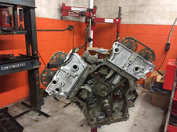 A car engine displayed on a stand inside a garage, showcasing its intricate components and mechanical design.