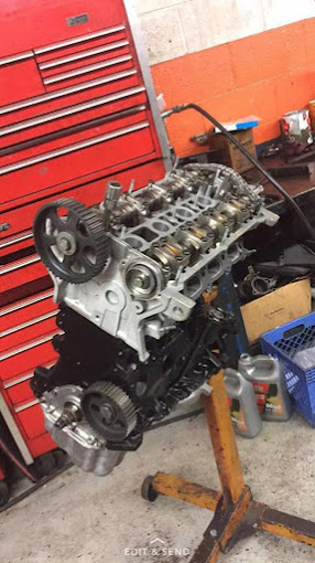 A car engine displayed on a stand, positioned in a well-organized garage environment.