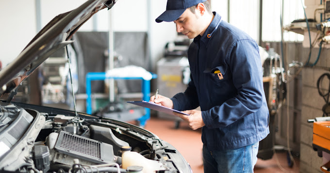 A man writes on a clipboard, focused on a car parked nearby, capturing details for inspection or evaluation.